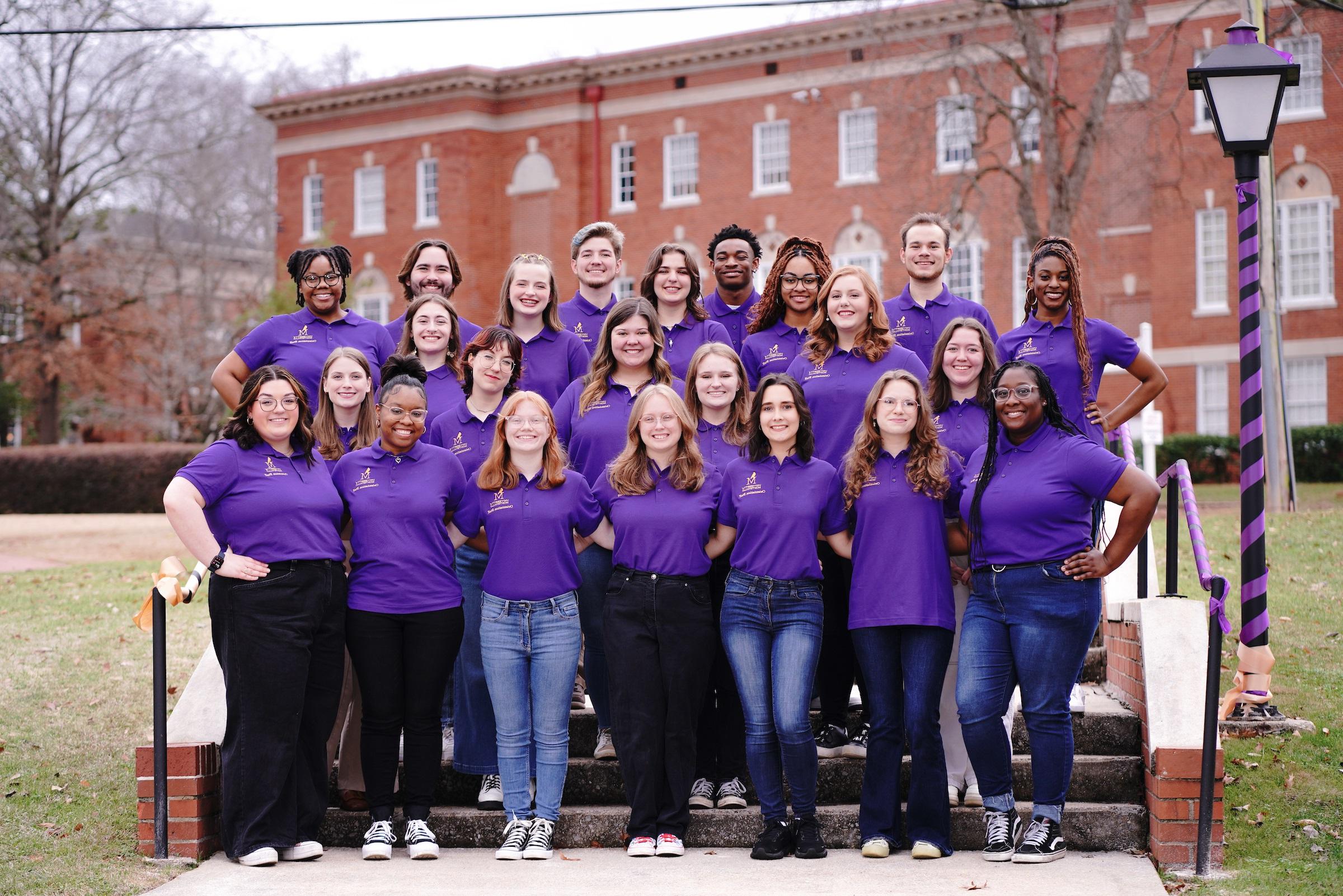 Photo of 2024 Orientation Staff wearing purple Orientation leader polo shirts and standing near Farmer Hall.
